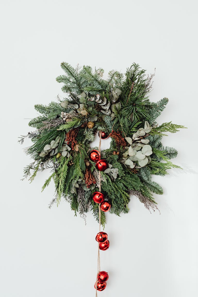 A beautiful Christmas wreath adorned with red bells on a white background.