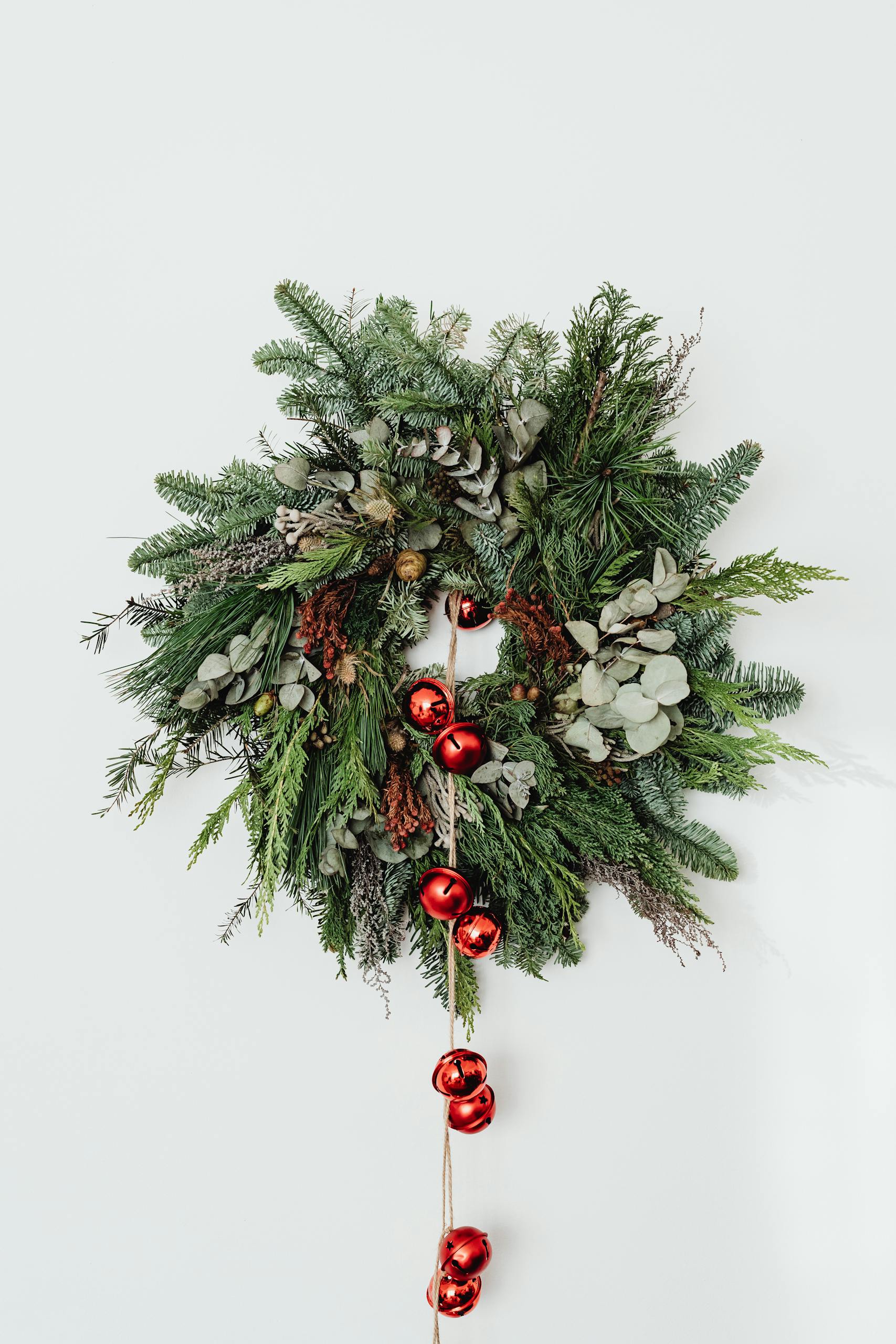 A beautiful Christmas wreath adorned with red bells on a white background.