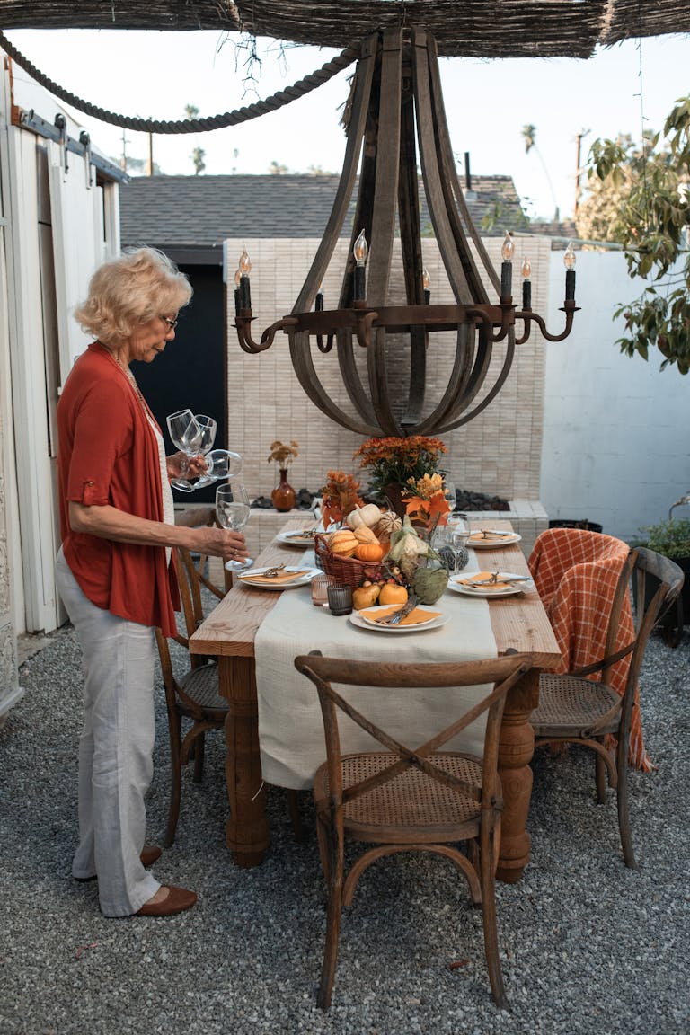 Elderly Woman Standing Beside a Table Holding Wine Glasses