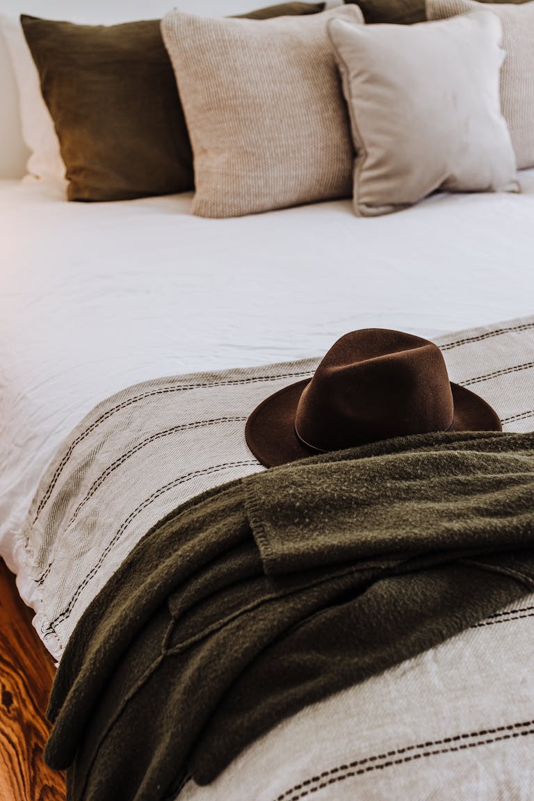 Felt hat on soft bed with decorative cushions