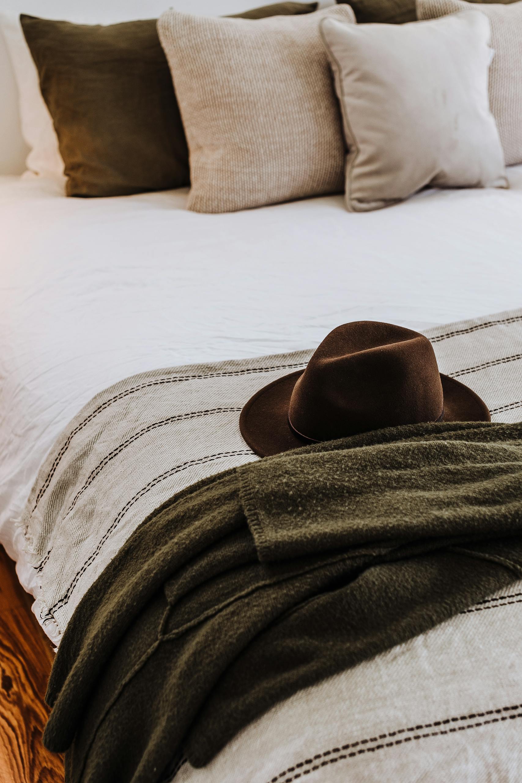 Felt hat on soft bed with decorative cushions