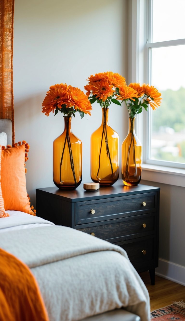 A bedroom with amber glass vases filled with orange flowers on a nightstand, dresser, and windowsill. Orange throw pillows and a rug add accents to the room