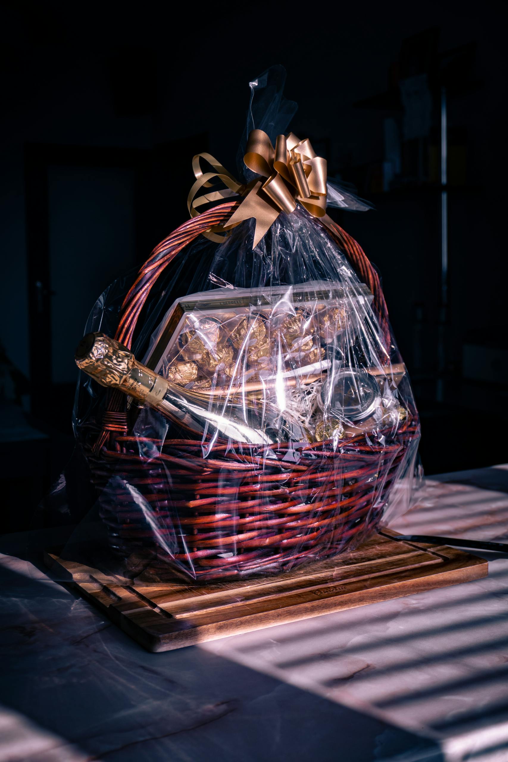 Luxurious gift basket featuring champagne and chocolates wrapped in cellophane with ribbon.