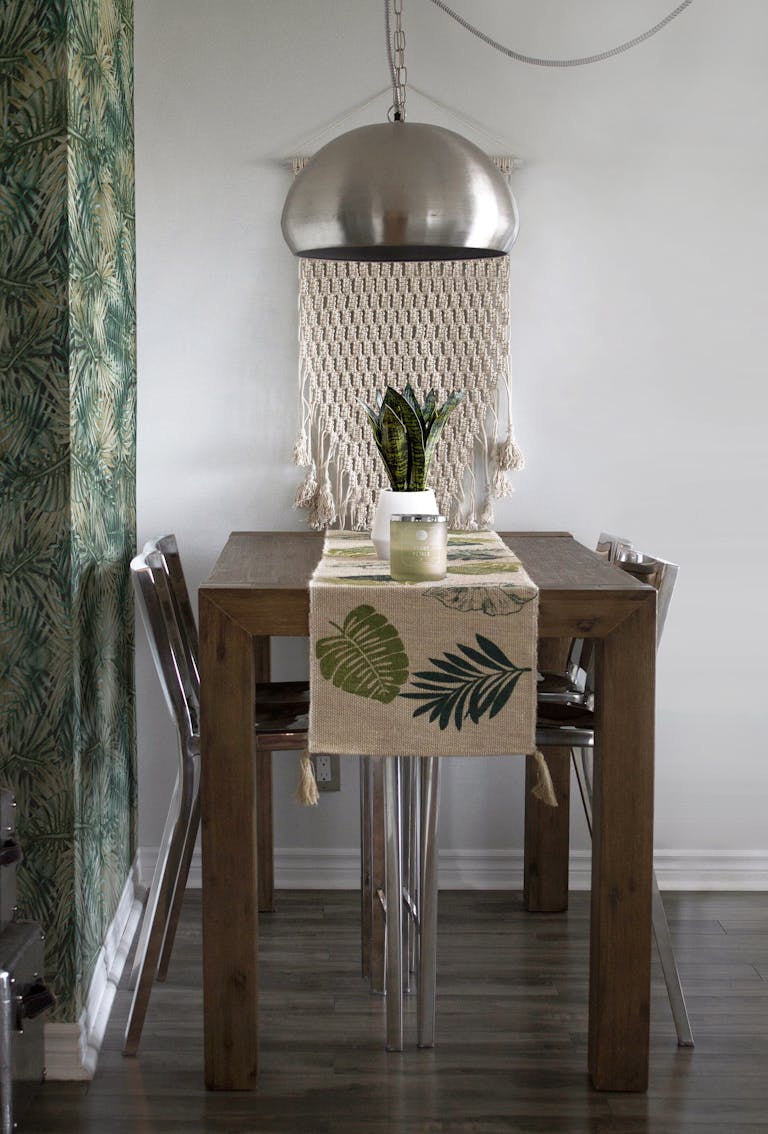 Modern dining setup with wood table, metal chairs, and tropical decor for a stylish interior feel.