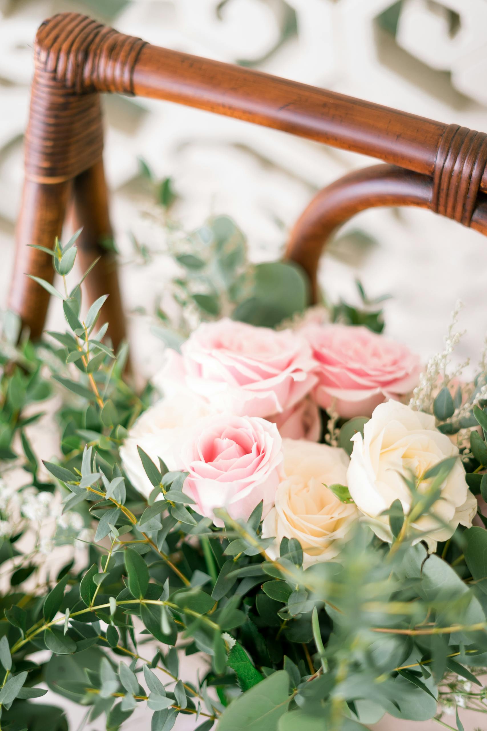 A beautiful bouquet of pink and white roses with lush greenery in a wicker basket.