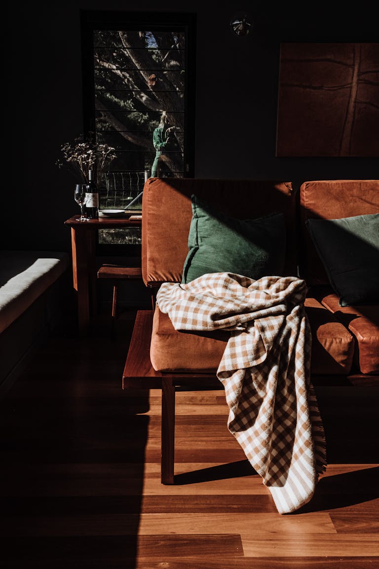 A stylish chair draped with a gingham blanket in a sunlit room filled with warm, rich tones.