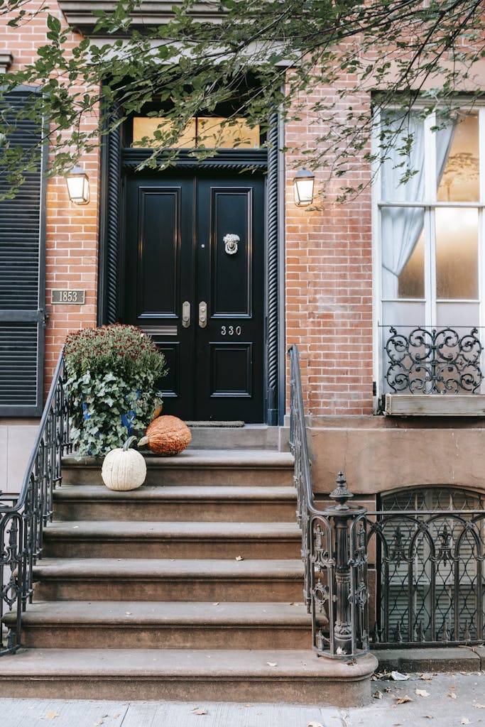 Charming townhouse entrance with pumpkins and plants, perfect for fall ambiance.