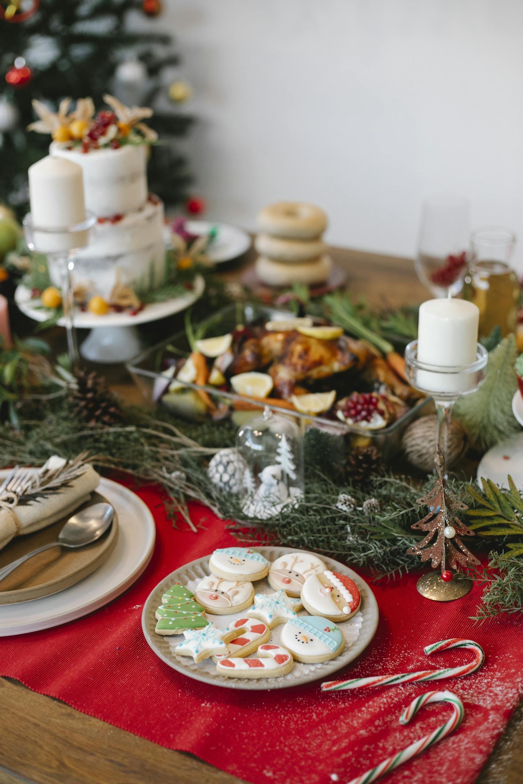 High angle of cake gingerbread placed near fried chicken on table decorated with candles and fir branches for Christmas celebration