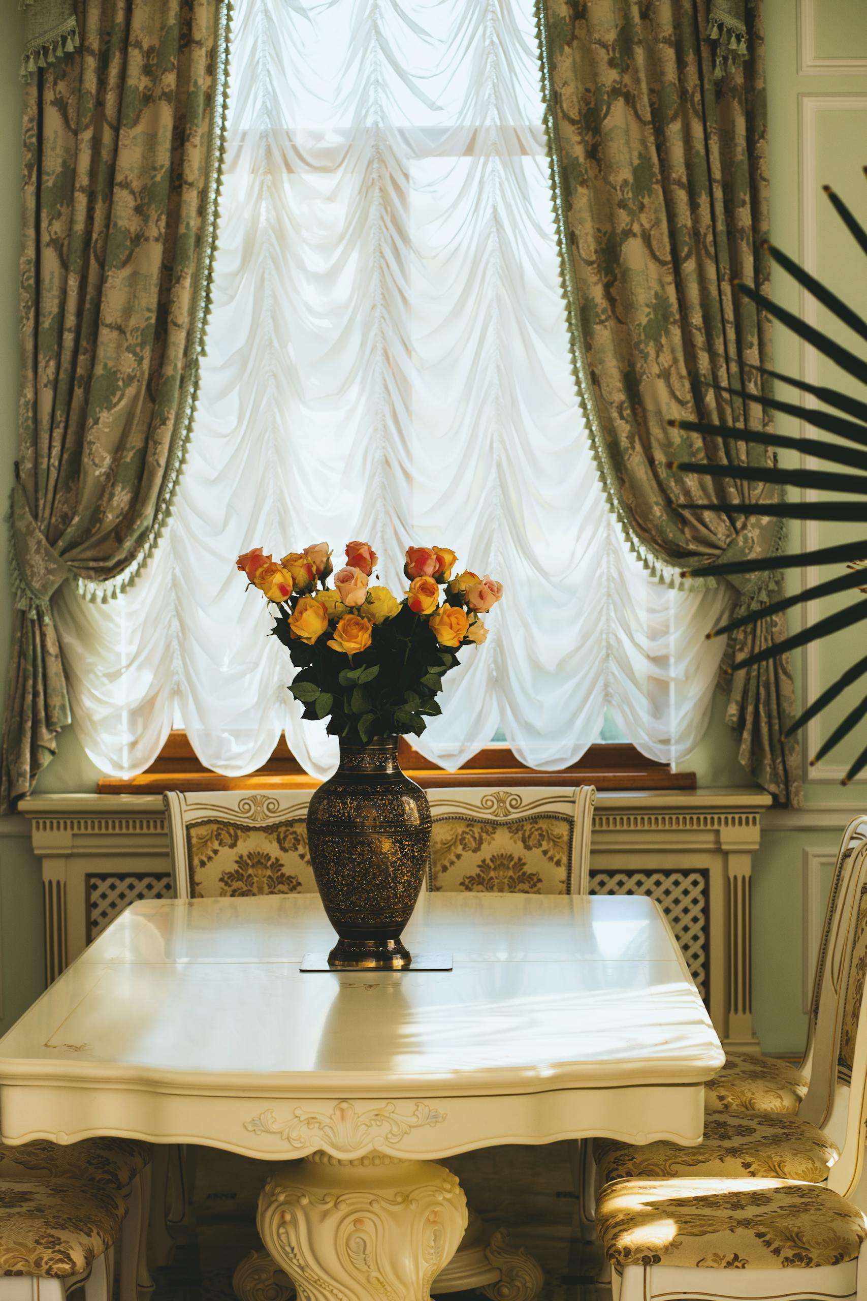 Luxurious dining room interior featuring ornate furniture and a floral centerpiece on the table.