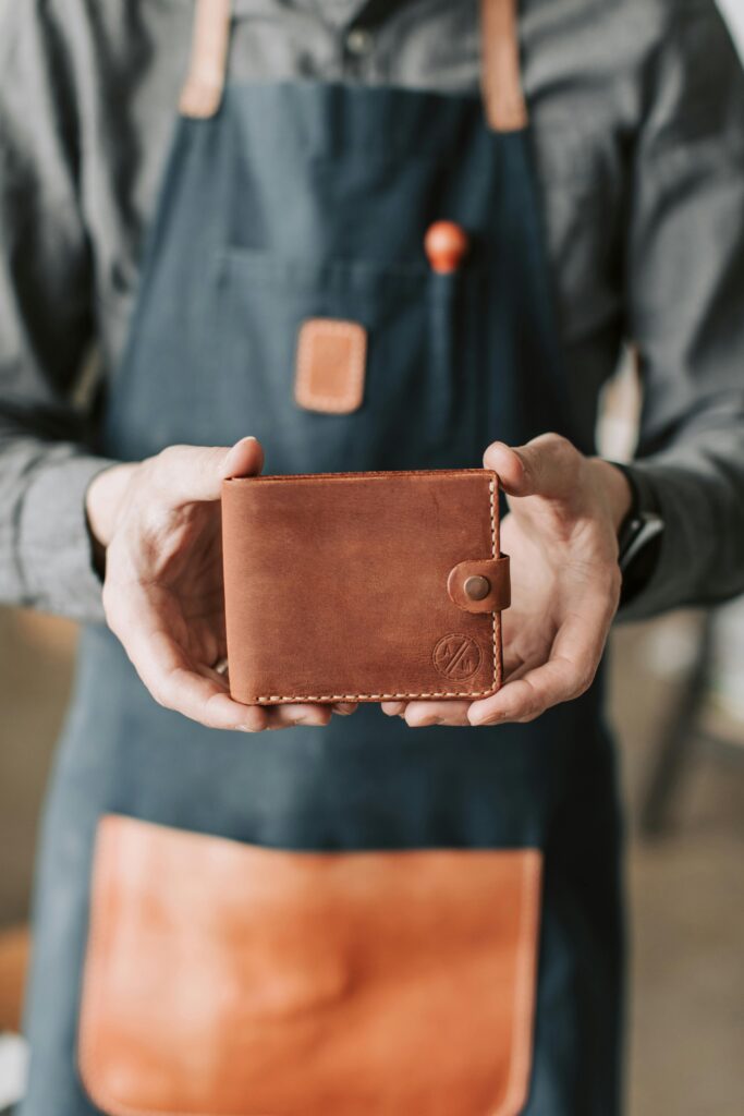 A craftsman holding a handmade leather wallet, showcasing artisanal craftsmanship.