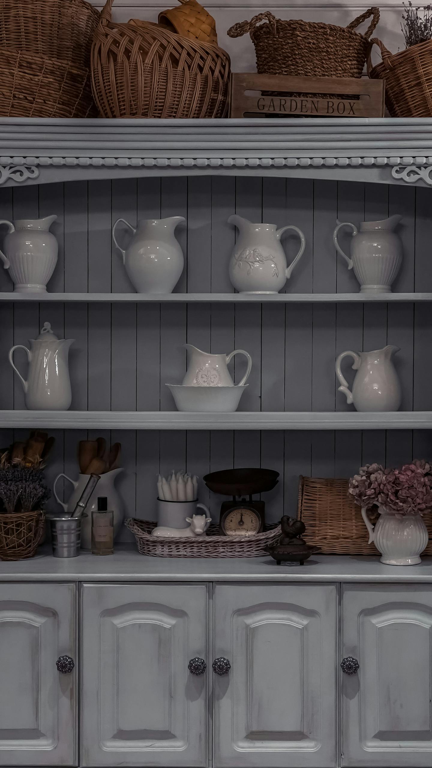 Rustic cabinet filled with ceramic kitchenware and decorative baskets.