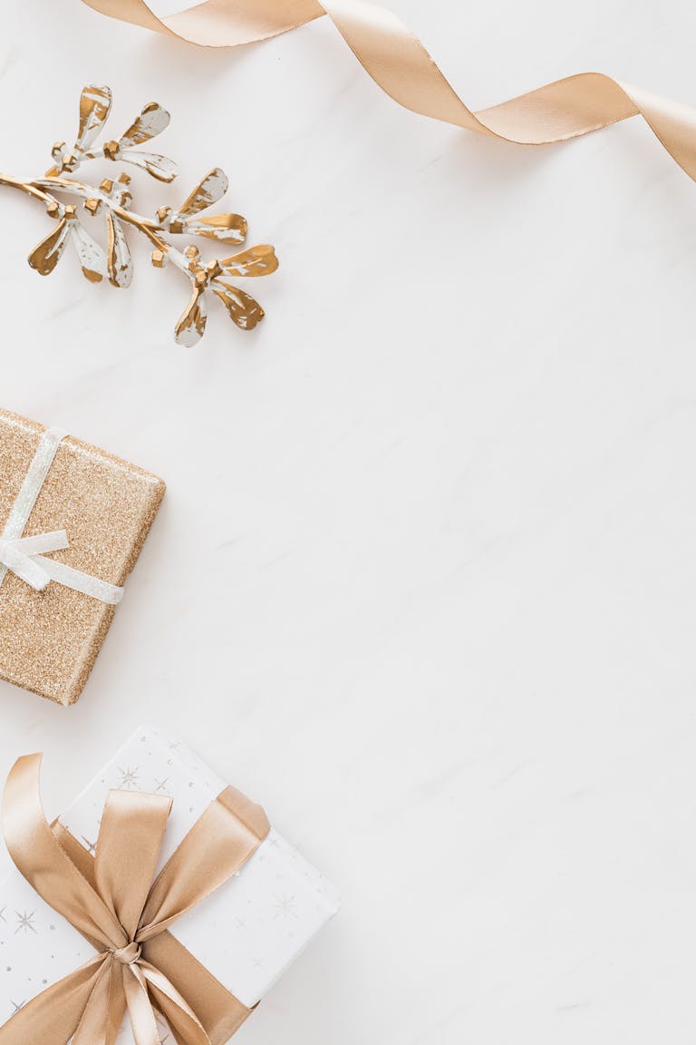 Stylish flat lay of Christmas gifts with golden accents on a white background, perfect for holiday themes.